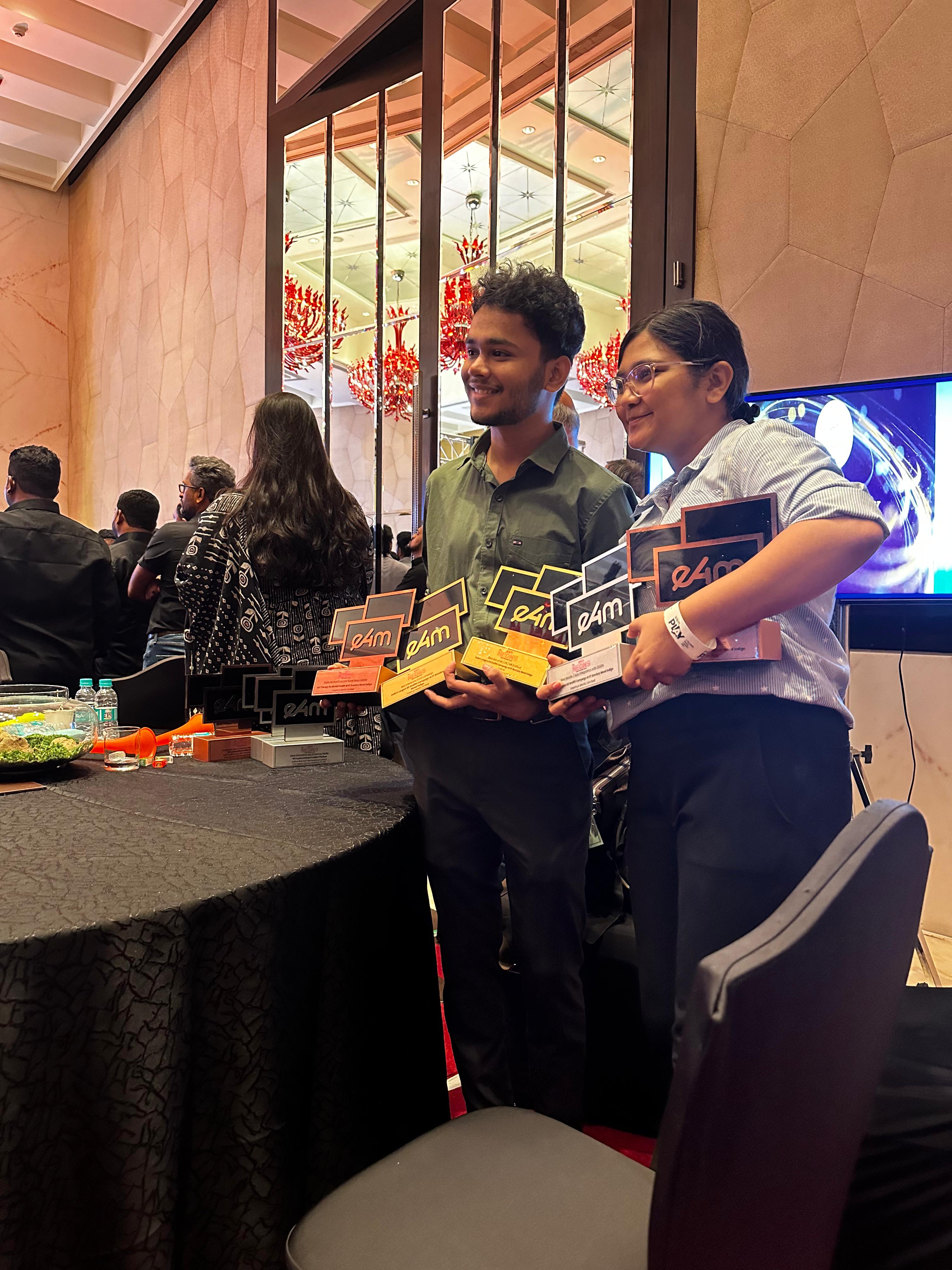 Nikhil holding e4m award trophies at the ceremony